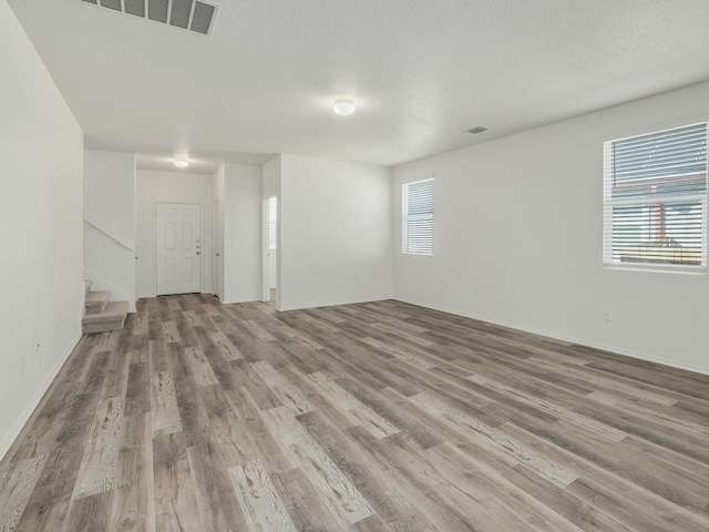 unfurnished room featuring hardwood / wood-style flooring, a wealth of natural light, and a textured ceiling