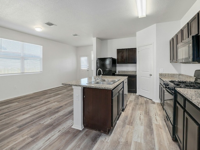 kitchen with dark brown cabinets, sink, a kitchen island with sink, and black appliances