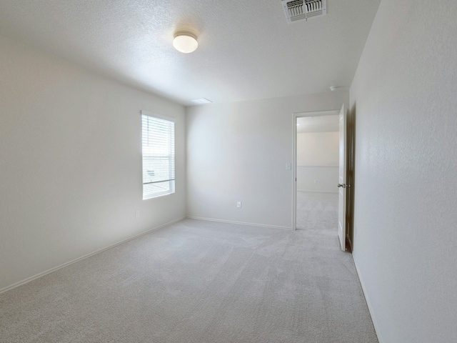 carpeted empty room featuring a textured ceiling