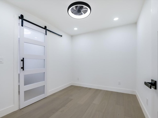 spare room with a barn door and light hardwood / wood-style floors