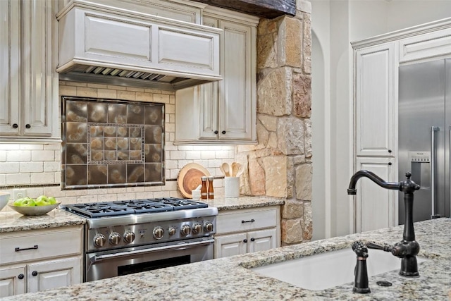 kitchen featuring sink, high quality appliances, premium range hood, and backsplash