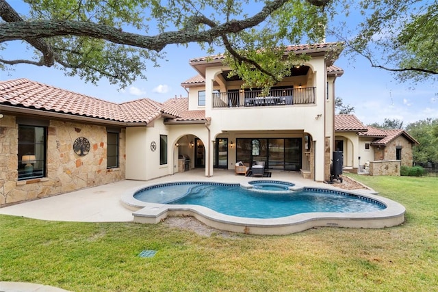 back of house featuring a patio, a balcony, a pool with hot tub, and a lawn