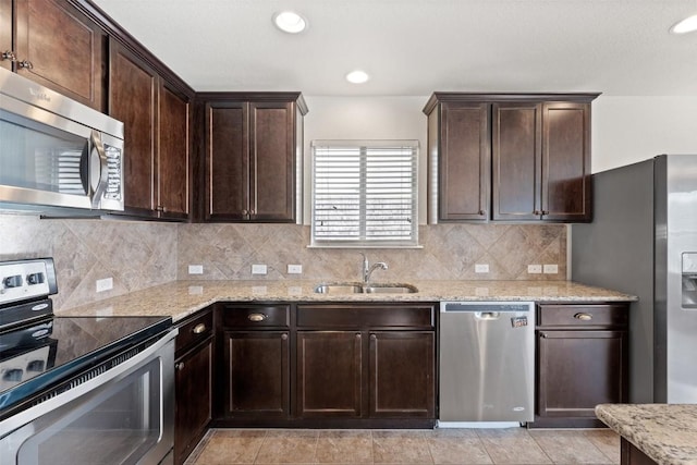 kitchen featuring tasteful backsplash, light stone countertops, sink, and appliances with stainless steel finishes