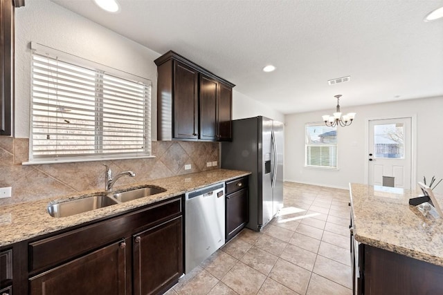 kitchen with sink, an inviting chandelier, backsplash, decorative light fixtures, and appliances with stainless steel finishes