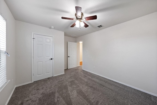 unfurnished bedroom with ceiling fan and dark colored carpet