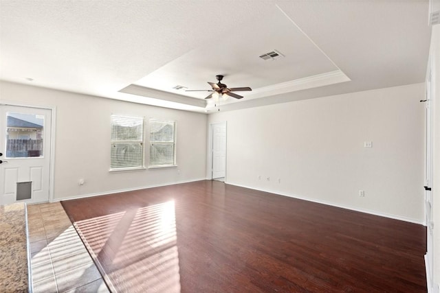 unfurnished room featuring a tray ceiling, ceiling fan, dark hardwood / wood-style flooring, and a textured ceiling