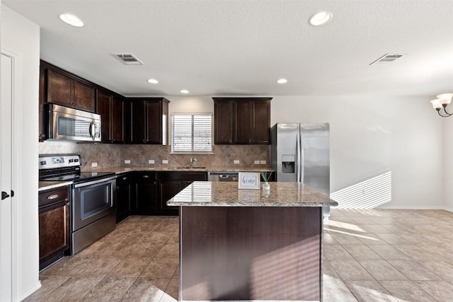 kitchen with a center island, sink, light stone countertops, tasteful backsplash, and stainless steel appliances