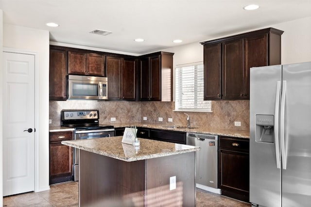 kitchen with a center island, sink, appliances with stainless steel finishes, tasteful backsplash, and light stone counters