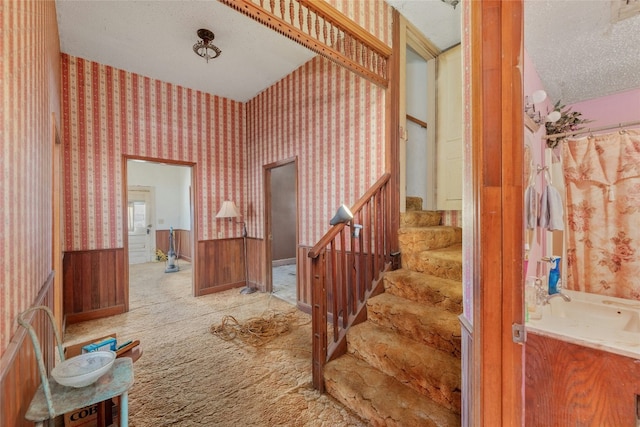 staircase with sink, carpet floors, and a textured ceiling