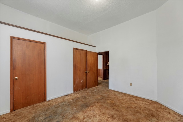 unfurnished bedroom featuring multiple closets, carpet, a textured ceiling, and baseboards