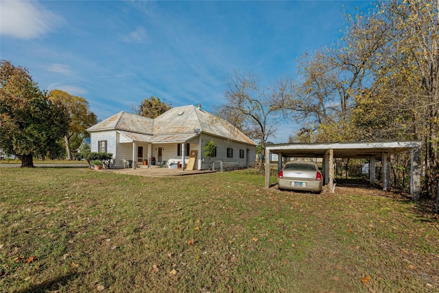 rear view of property with a detached carport and a yard