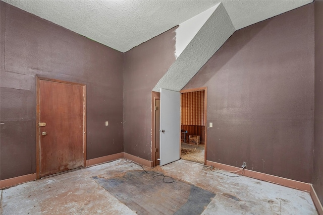 interior space with high vaulted ceiling, baseboards, and a textured ceiling