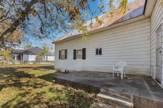 view of property exterior with a patio area, metal roof, and a lawn