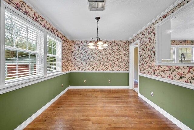 20024 W Lakeshore Dr, Magnolia, TX 77355 - unfurnished dining area with a chandelier, wood finished floors, crown molding, and wallpapered walls