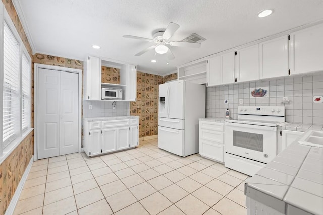 20024 W Lakeshore Dr, Magnolia, TX 77355 - kitchen with white appliances, tile countertops, wallpapered walls, open shelves, and white cabinetry