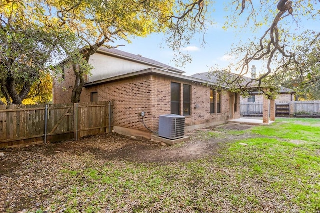 rear view of house featuring central AC unit and a lawn