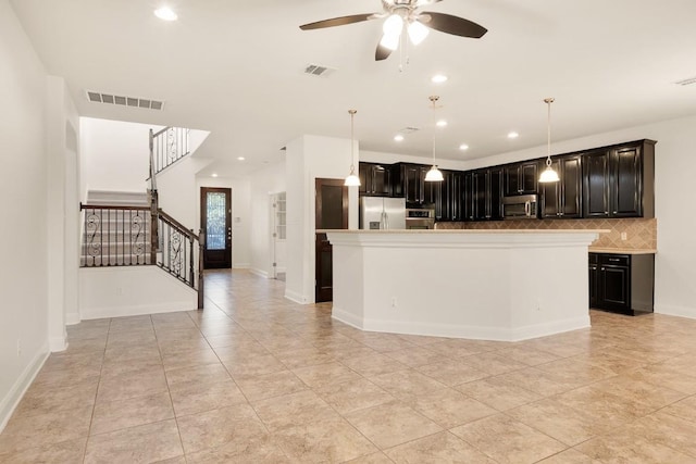 kitchen with ceiling fan, appliances with stainless steel finishes, tasteful backsplash, decorative light fixtures, and a kitchen island