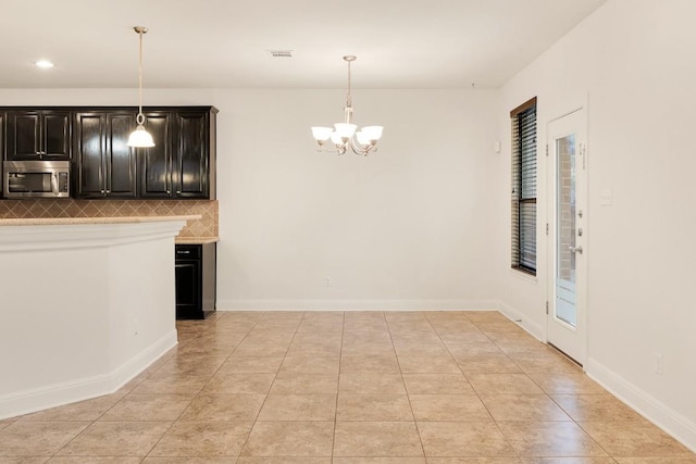 kitchen featuring pendant lighting, decorative backsplash, light tile patterned floors, and a chandelier