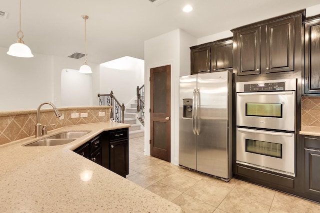 kitchen with backsplash, sink, hanging light fixtures, appliances with stainless steel finishes, and dark brown cabinetry