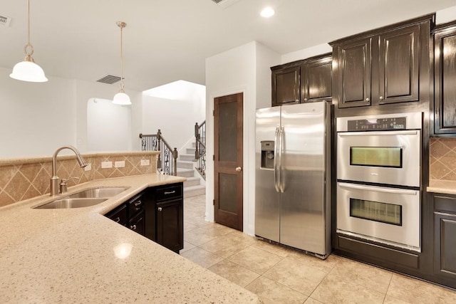 11125 Bastogne Loop, Austin, TX 78739 - kitchen featuring appliances with stainless steel finishes, backsplash, light tile patterned floors, hanging light fixtures, and light stone counters