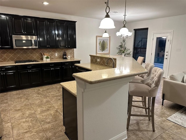 11125 Bastogne Loop, Austin, TX 78739 - kitchen featuring stainless steel appliances, dark cabinetry, tasteful backsplash, a breakfast bar, and a large island with sink