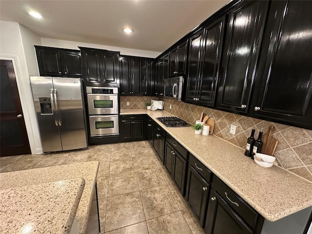 11125 Bastogne Loop, Austin, TX 78739 - kitchen featuring dark cabinets, appliances with stainless steel finishes, tasteful backsplash, light stone counters, and recessed lighting