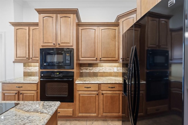 kitchen with backsplash, light stone countertops, and black appliances