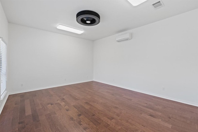 empty room with an AC wall unit and dark wood-type flooring