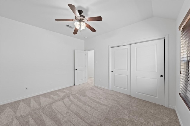 unfurnished bedroom featuring ceiling fan, a closet, light colored carpet, and vaulted ceiling