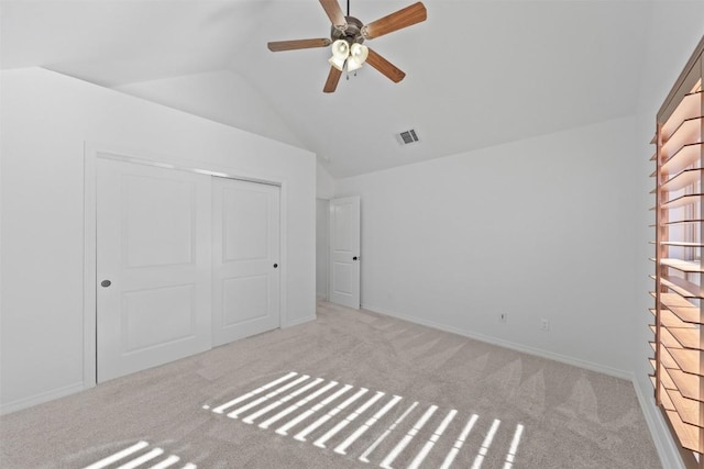 unfurnished bedroom with light colored carpet, a closet, lofted ceiling, and ceiling fan