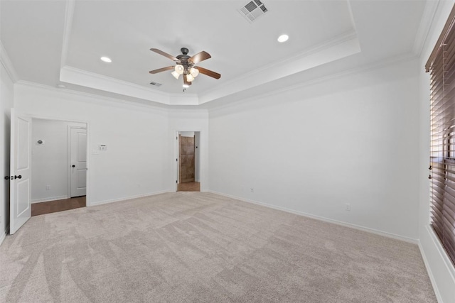 unfurnished bedroom featuring light carpet, a tray ceiling, ceiling fan, and ornamental molding