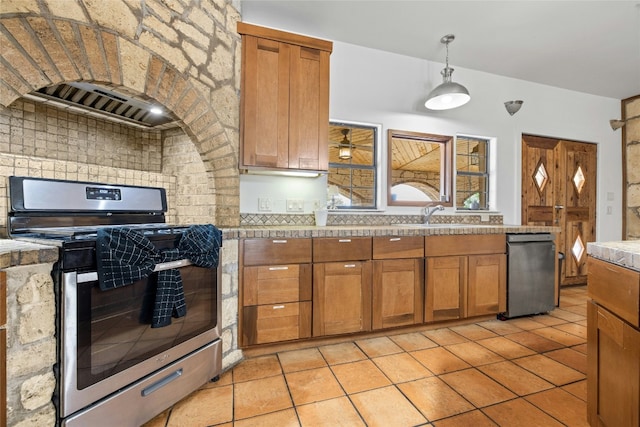 kitchen with stainless steel range, light tile patterned floors, pendant lighting, and range hood