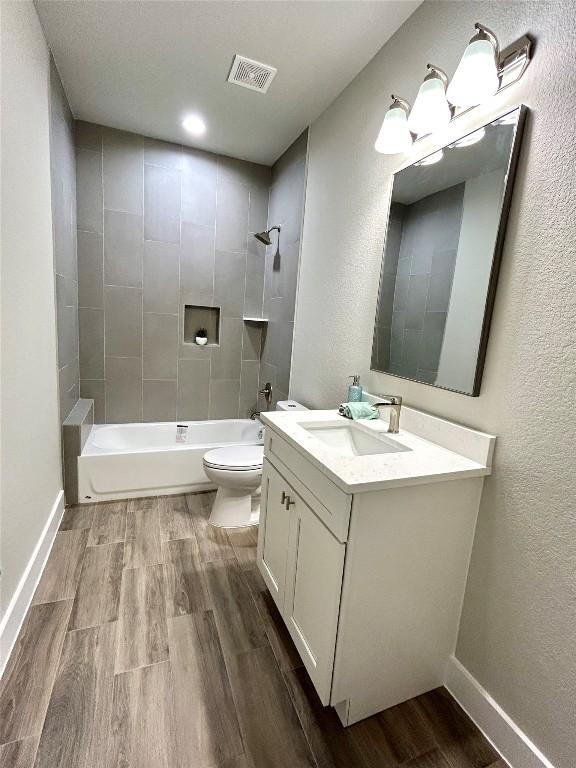 full bathroom featuring toilet, hardwood / wood-style floors, vanity, and tiled shower / bath