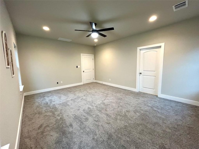 empty room featuring ceiling fan and dark carpet