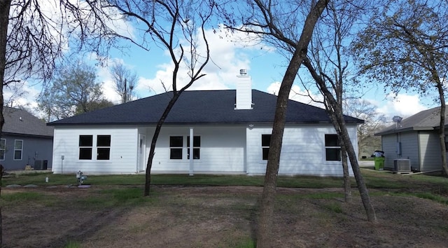 rear view of house with central air condition unit and a yard