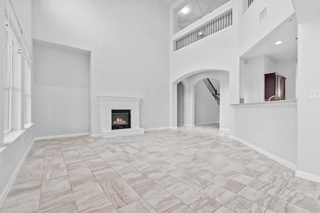 unfurnished living room featuring a towering ceiling and a high end fireplace