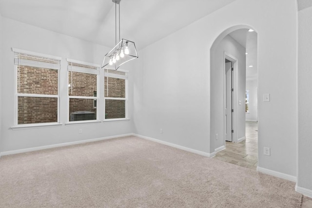 unfurnished room with light colored carpet and an inviting chandelier