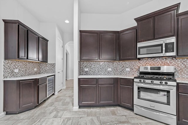 kitchen with backsplash, stainless steel appliances, wine cooler, and dark brown cabinetry