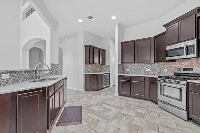 kitchen featuring appliances with stainless steel finishes, backsplash, dark brown cabinetry, and sink