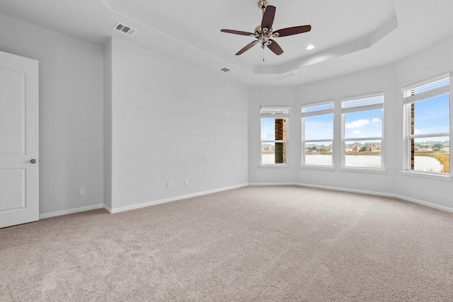 carpeted empty room featuring a raised ceiling and ceiling fan