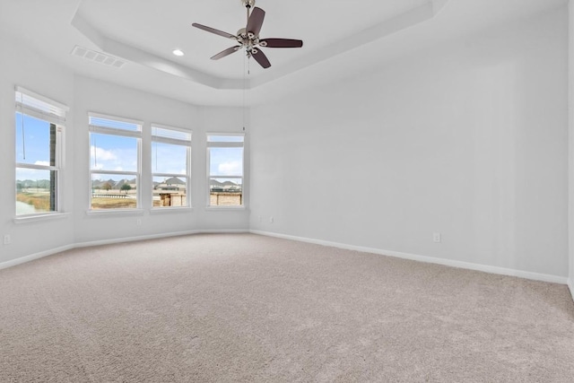 carpeted empty room with a tray ceiling and ceiling fan