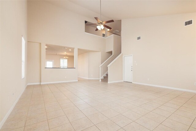 empty room featuring ceiling fan with notable chandelier, light tile patterned floors, and high vaulted ceiling