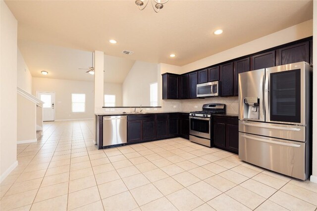 kitchen featuring appliances with stainless steel finishes, tasteful backsplash, sink, lofted ceiling, and light tile patterned flooring