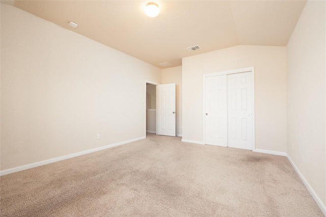 unfurnished bedroom with carpet flooring, a closet, and lofted ceiling