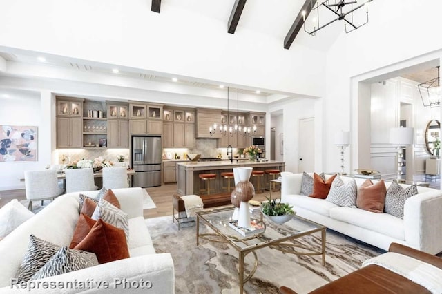 living room with sink, light hardwood / wood-style flooring, high vaulted ceiling, a notable chandelier, and beamed ceiling