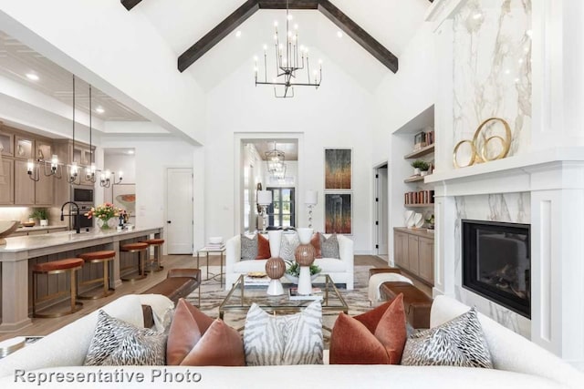 living room featuring sink, a premium fireplace, light hardwood / wood-style flooring, beamed ceiling, and high vaulted ceiling