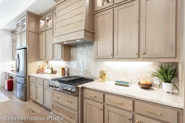 kitchen with light wood-type flooring, premium range hood, light brown cabinetry, and stainless steel appliances