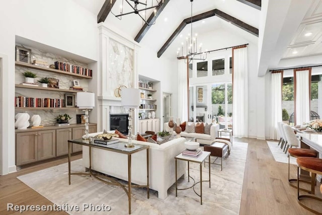 living room featuring high vaulted ceiling, beamed ceiling, a chandelier, and light wood-type flooring