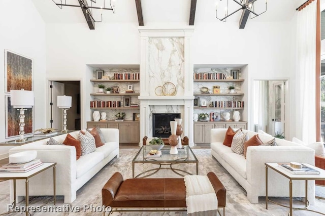 living room with beamed ceiling, a towering ceiling, a high end fireplace, and a chandelier