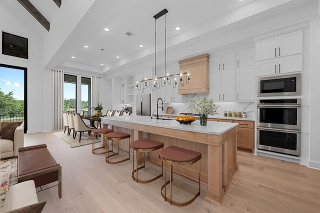 790 Old Stone Rd, Austin, TX 78737 - kitchen featuring stainless steel double oven, black microwave, light countertops, light wood finished floors, and a kitchen breakfast bar